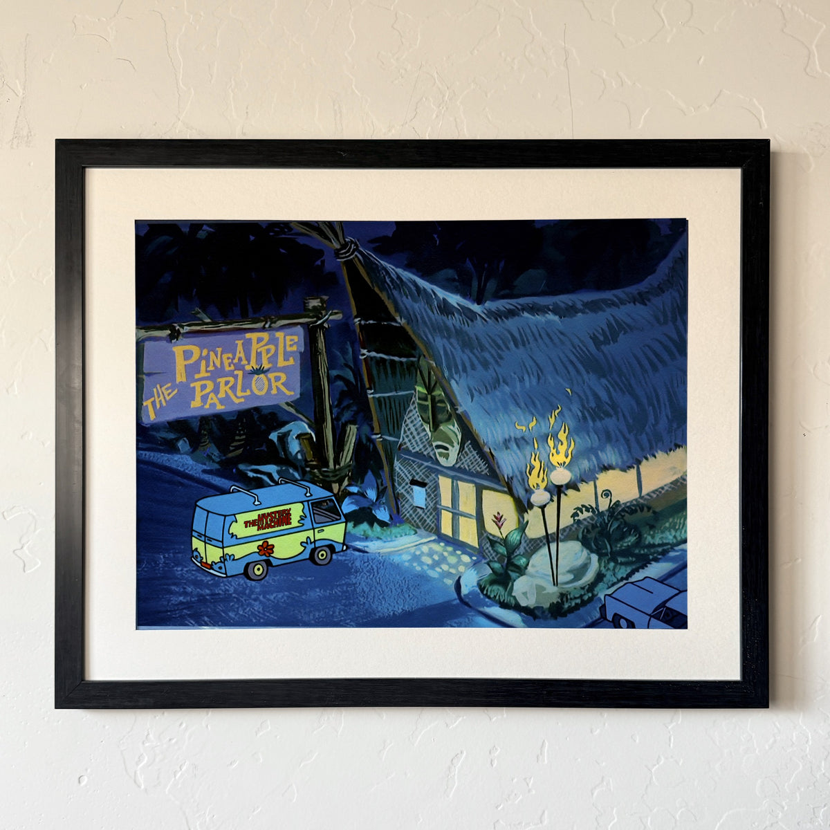 Tiki Parlor print, matted and framed in a black frame, hanging on a wall