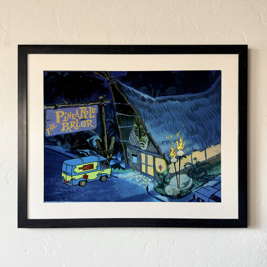 Tiki Parlor print, matted and framed in a black frame, hanging on a wall